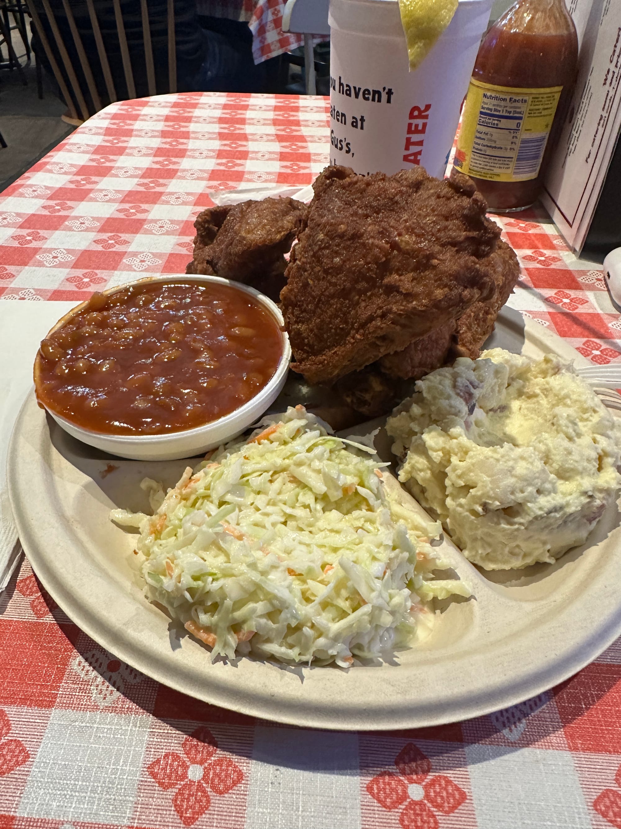 A plate of fried chicken with beans, cole slaw, and potato salad. 